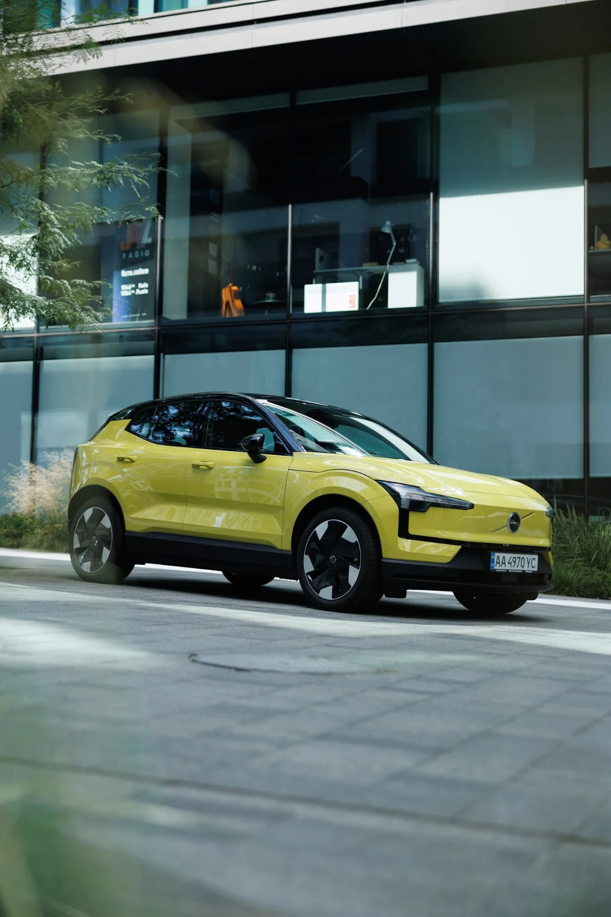 Yellow Volvo electric SUV by a glass building